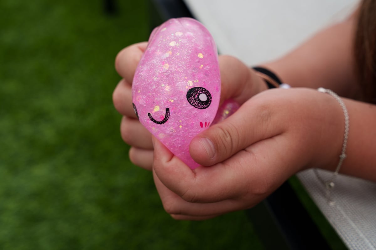 Child's hand squeezing a pink glitter squishy dumpling toy